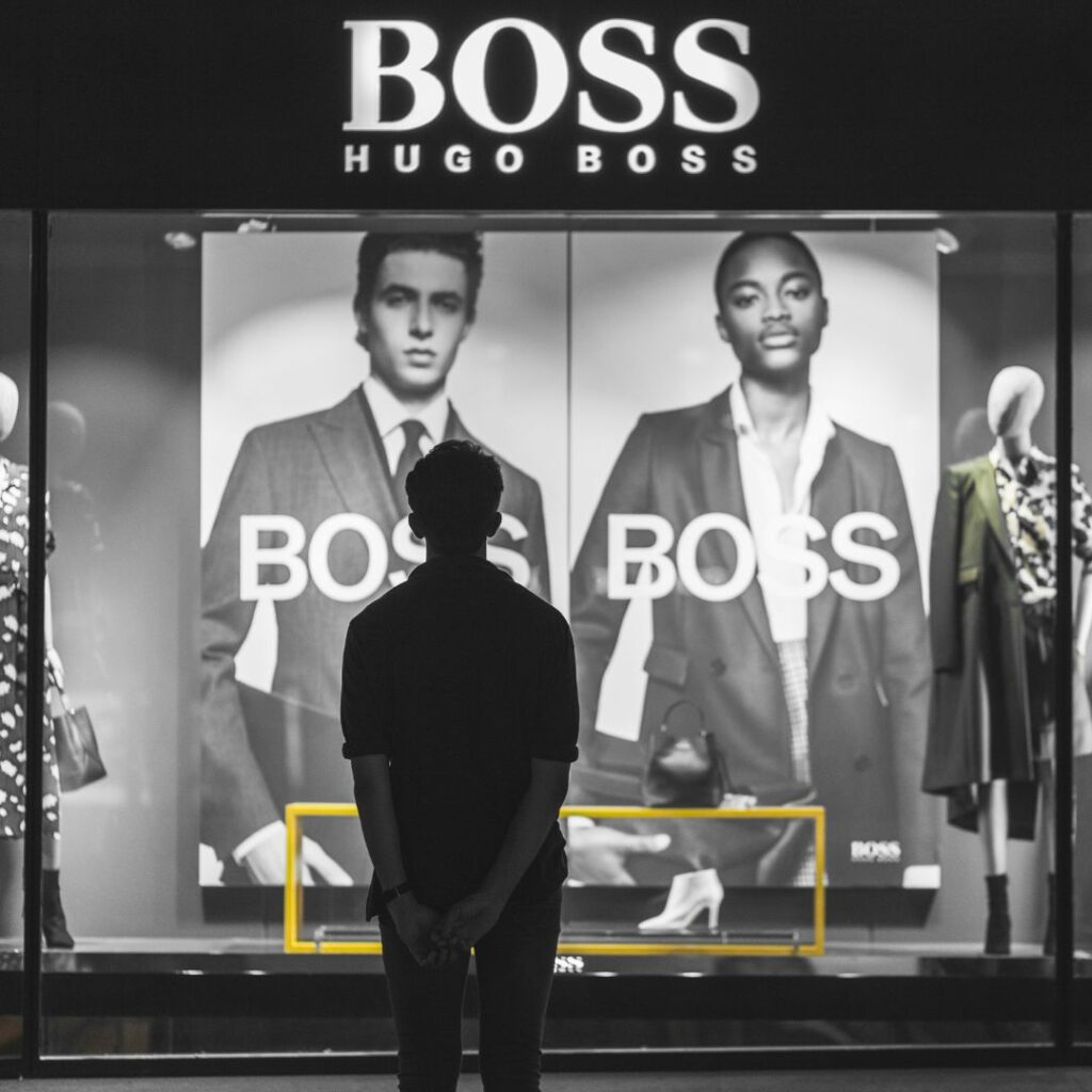 Ung man tittar på en Hugo Boss skyltfönster Ung man tittar på en Hugo Boss skyltfönster med drömmar och visioner där han en dag vill bära Hugo Boss parfym och kläder.