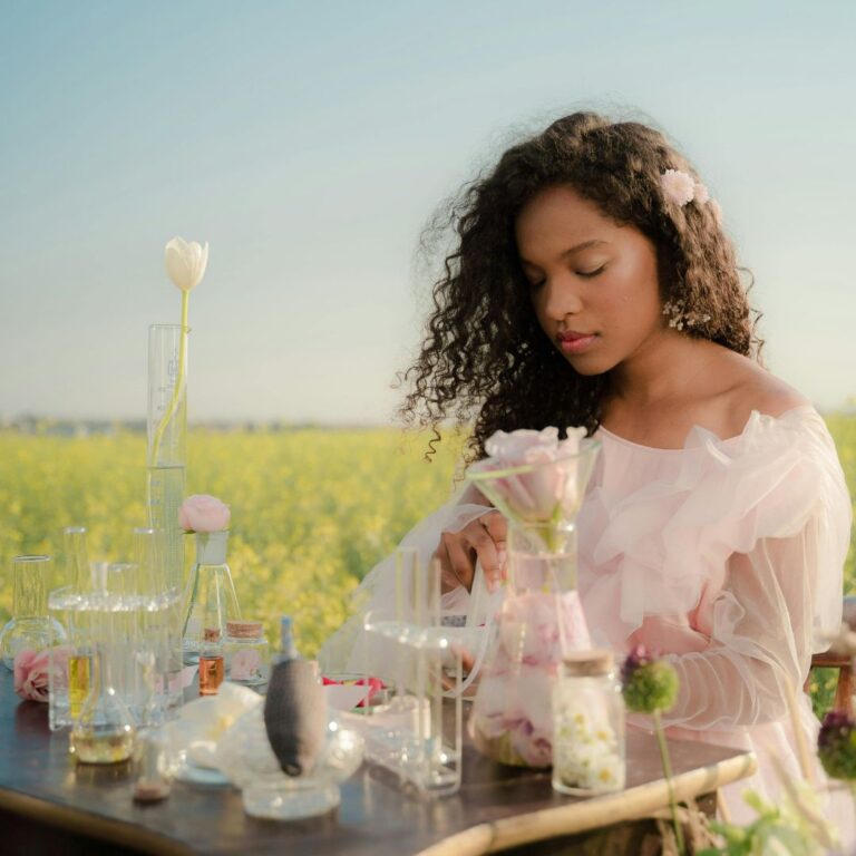 Vetiver parfymer placerad på ett bord utomhus med blommor och andra doftnoter som en kvinna använder.