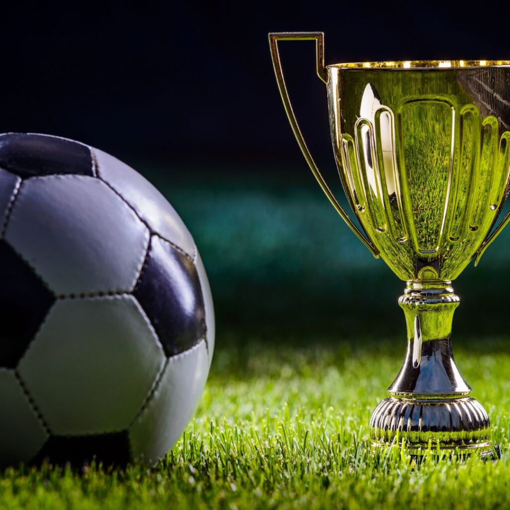 En fotboll bredvid en guldpokal på en fotbollsplan som representerar bästa fotbollsparfym för fotbollsmatcher.