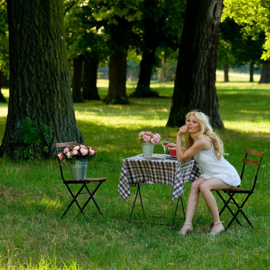 Dam ensam på Singles Day på en ensam picknick med blommor, dryck och vin. Hon doftar självsäkert och feminint och lever livet ensam just nu.