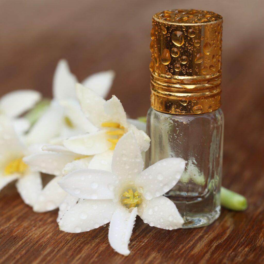 Tuberos parfym i glass behållare med tuberosblommor bredvid för att symbolisera dess underbara tuberosdoft.