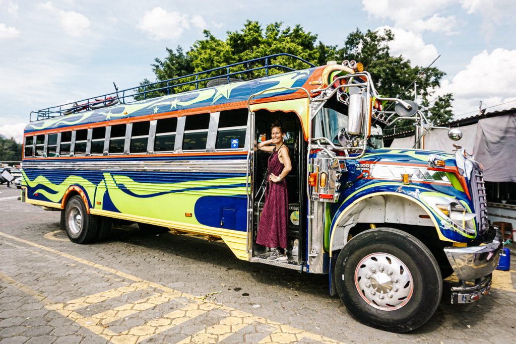 woman in front of colorful bus | Things to do in Guatemala travel tips