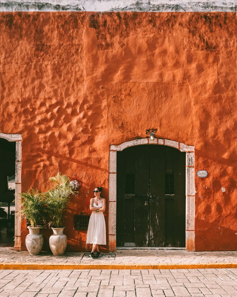 Deborah voor oranje gekleurd huis in Valladolid in Mexico.