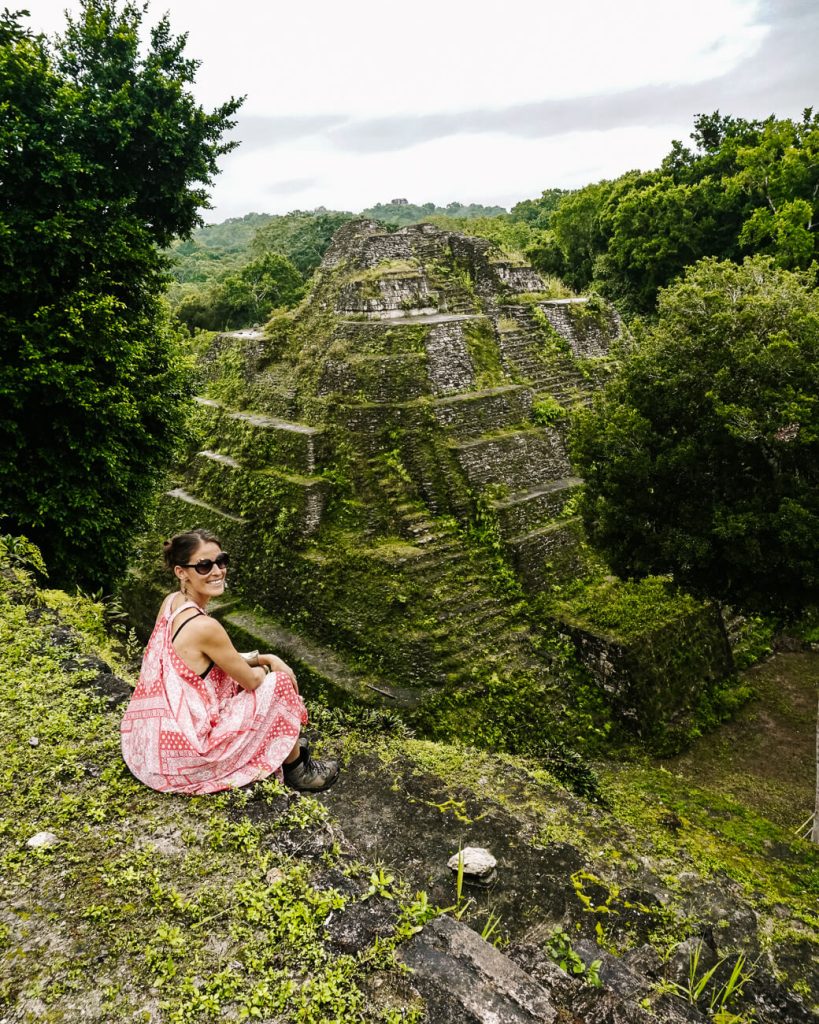 Deborah at northern acropolis with view of temple 216 during a Yaxha tour in Guatemala