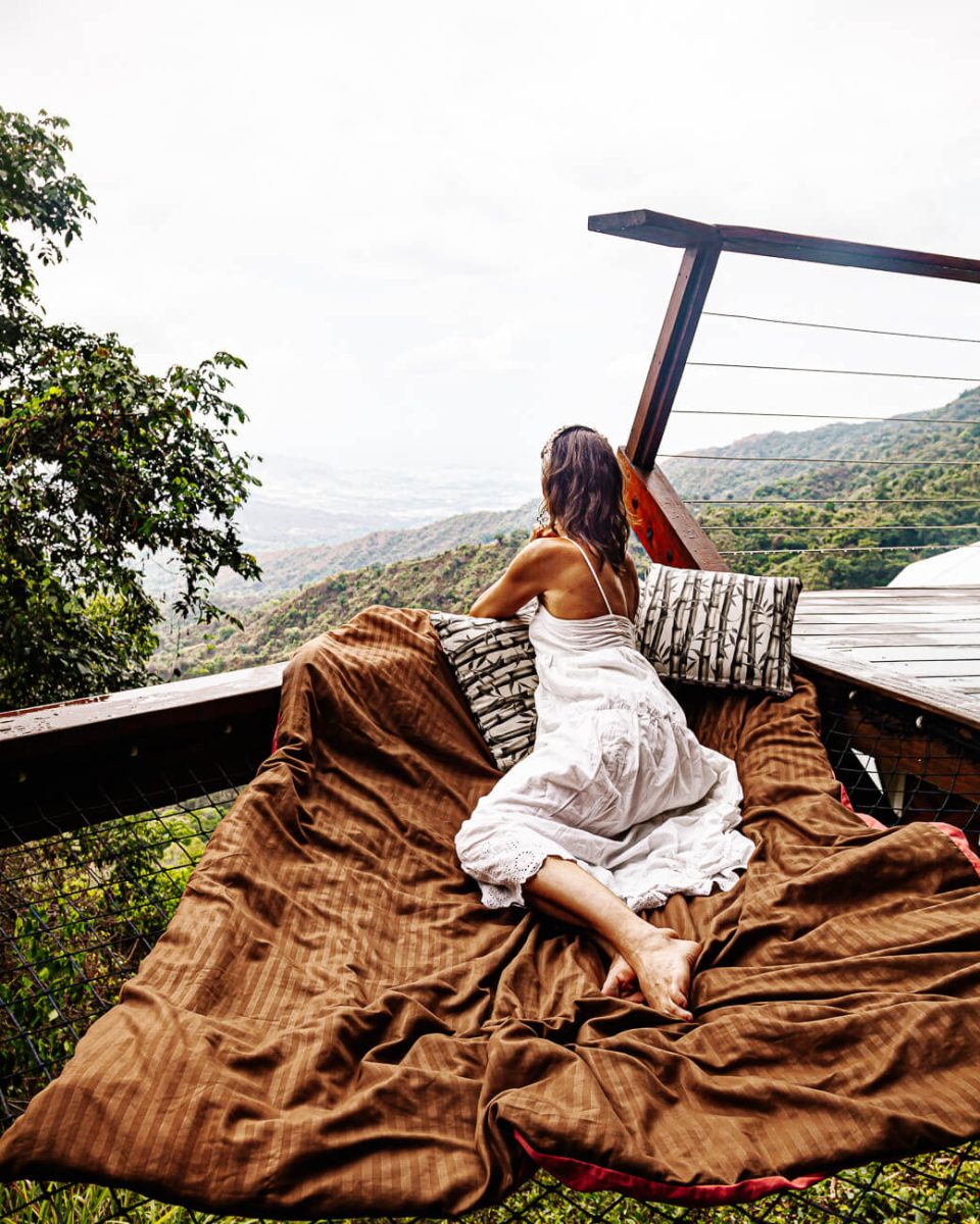 Deborah in hangmat genietend van uitzicht op Santa Marta en kust vanaf Trekker Glamping Minca in Colombia