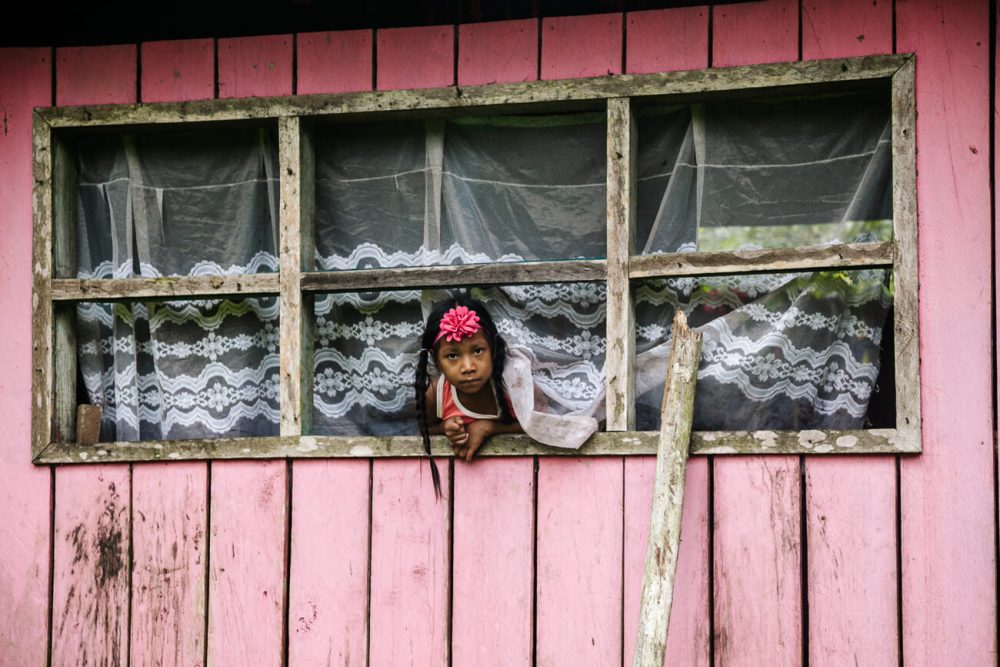 child hanging out of window in Mocagua village