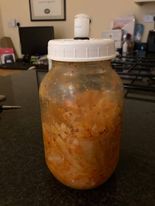 Jar of orangey finely chopped vegatables with a white lid with a tube poking out of the top