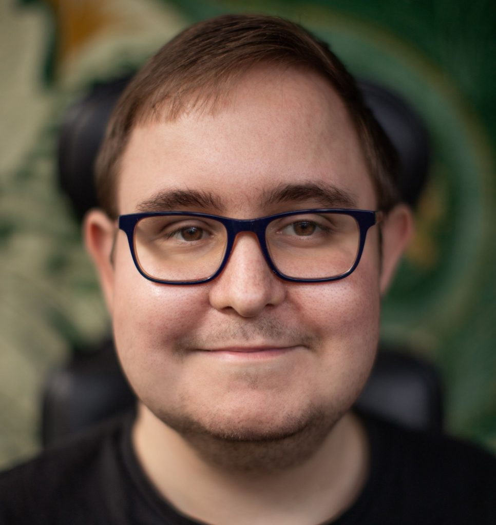 Adam Langley, a headshot of a white man with short brown hair and black glasses