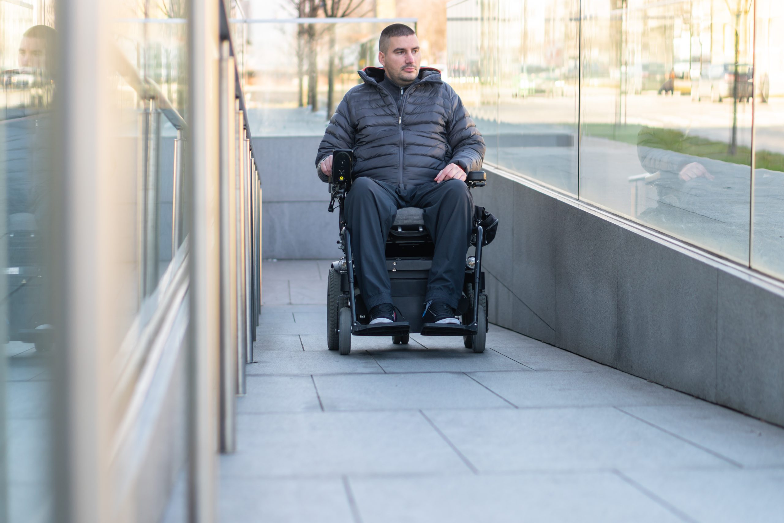 Man in a power wheelchair entering a building via a ramp