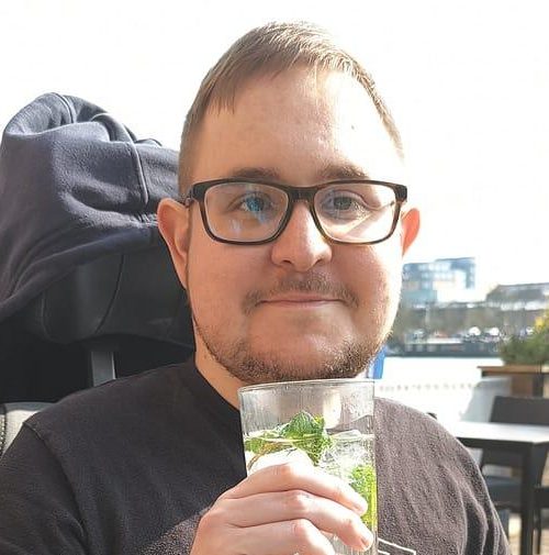 Adam's holding a mojito glass with a black state champs shirt with a tiger on it and glasses.