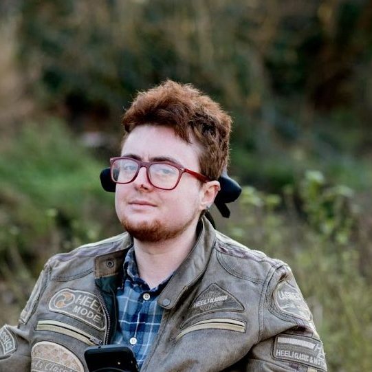 Jamie Hale, a white person with red hair in an electric wheelchair