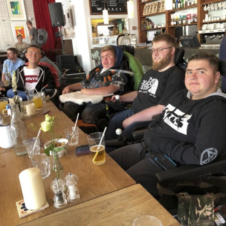 A group of young men in electric wheelchairs seated at a pub table