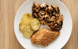 Foto van de kipfilet vergezeld van champignons en schijfjes aardappel