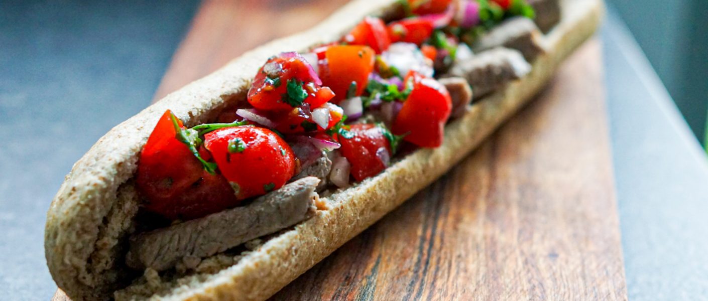 Foto van de steak sandwich geserveerd op een houten plank.