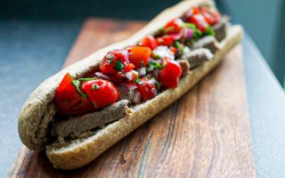 Foto van de steak sandwich geserveerd op een houten plank.