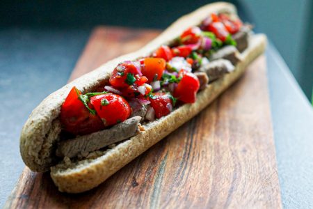 Foto van de steak sandwich geserveerd op een houten plank.