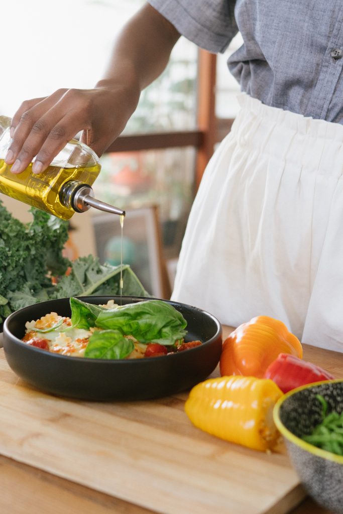 Foto van een vrouw die olie op een salade doet.