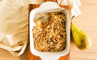 Foto van de perencrumble in een ovenschotel en met een gouden lepel.