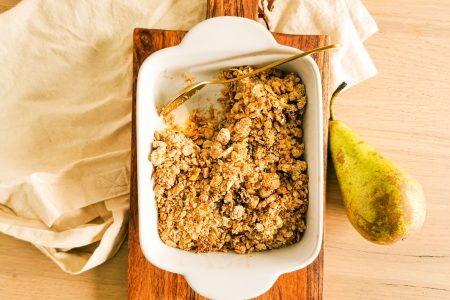 Foto van de perencrumble in een ovenschotel en met een gouden lepel.