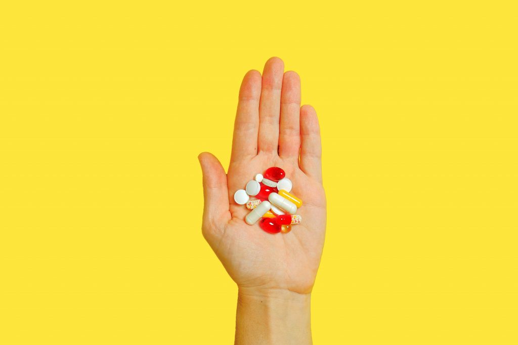 Foto van een hand met daarin verschillende vitaminepillen.