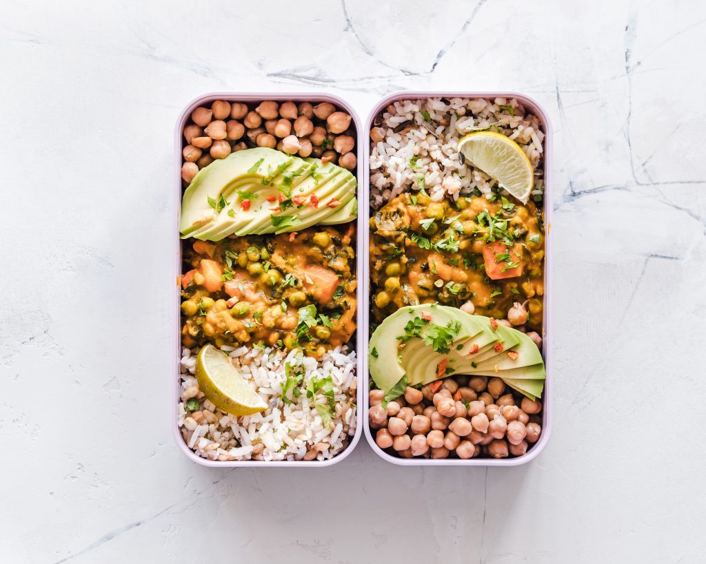 Foto van twee identieke salades met groenten, peulvruchten en avocado.