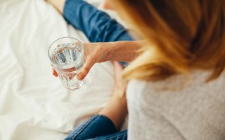 Foto van een vrouw met een glas water in de hand.