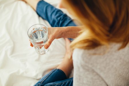 Foto van een vrouw met een glas water in de hand.