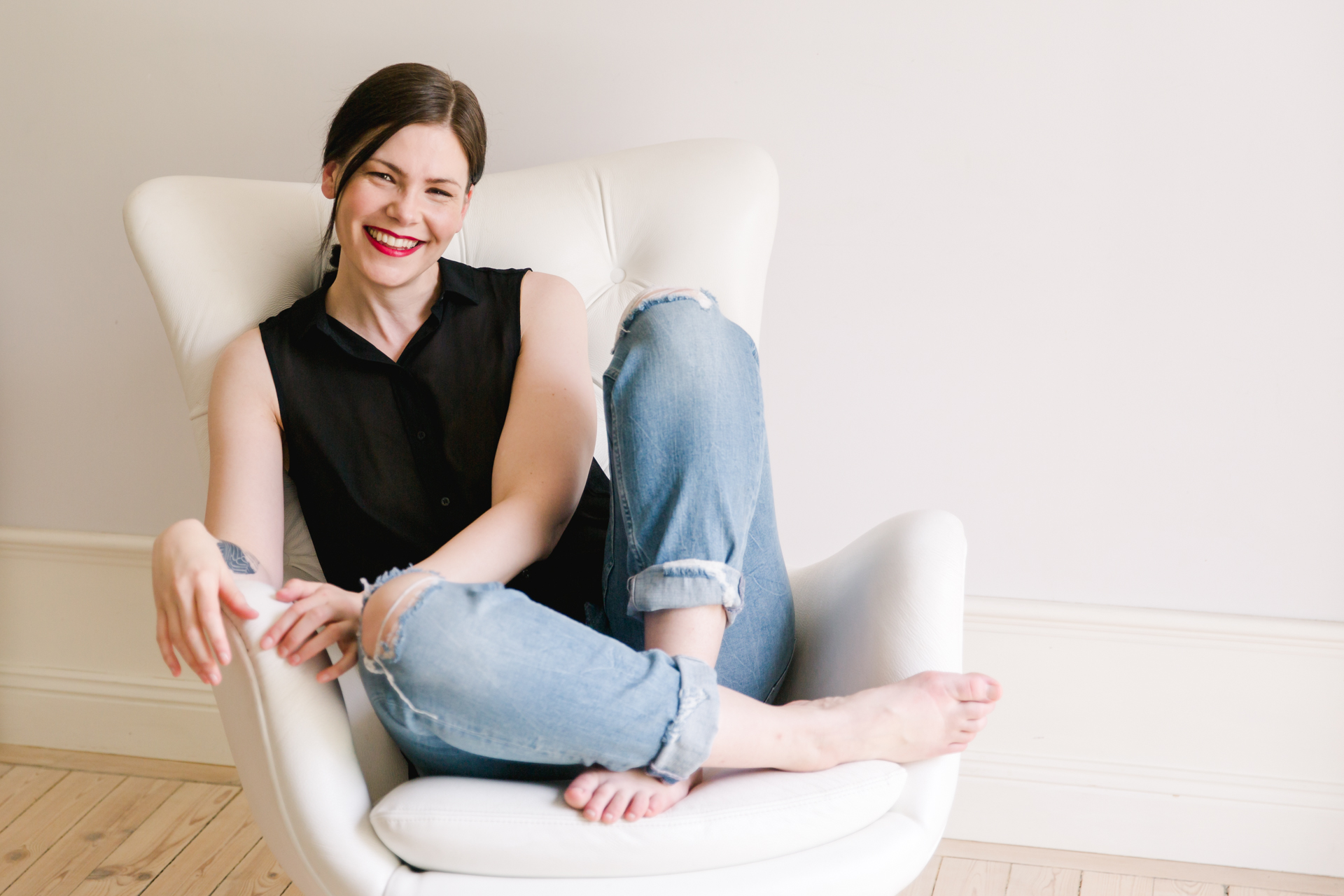 A branding photo of a smiling entrepreneur wearing jeans and a black top