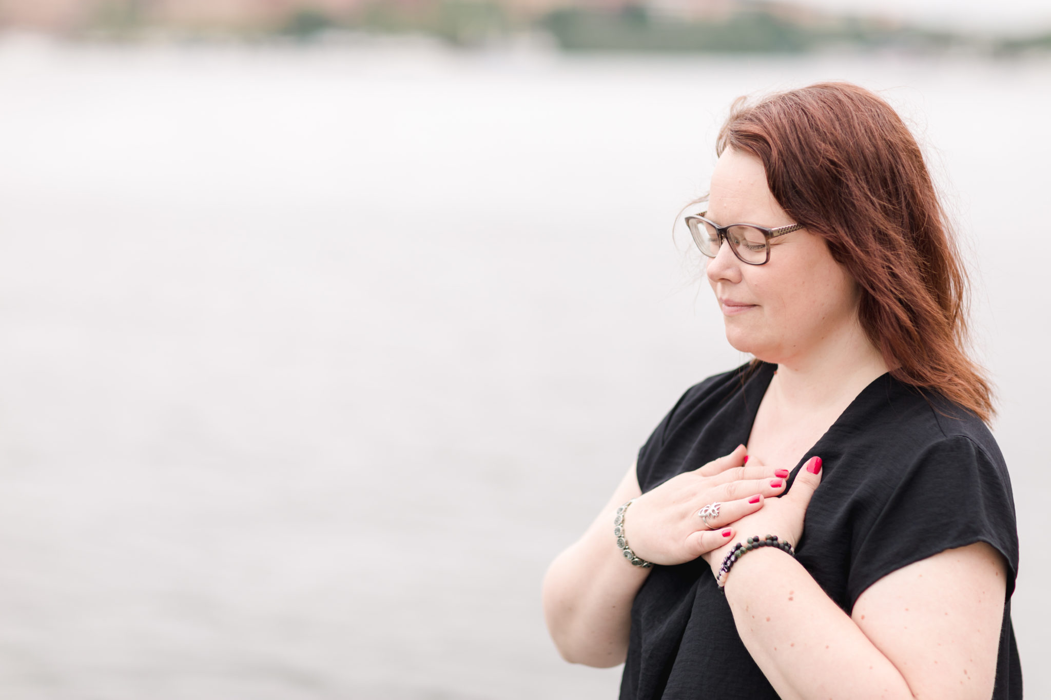 Author, Jenny Sandfors, relaxing with her hands on her chest by the water