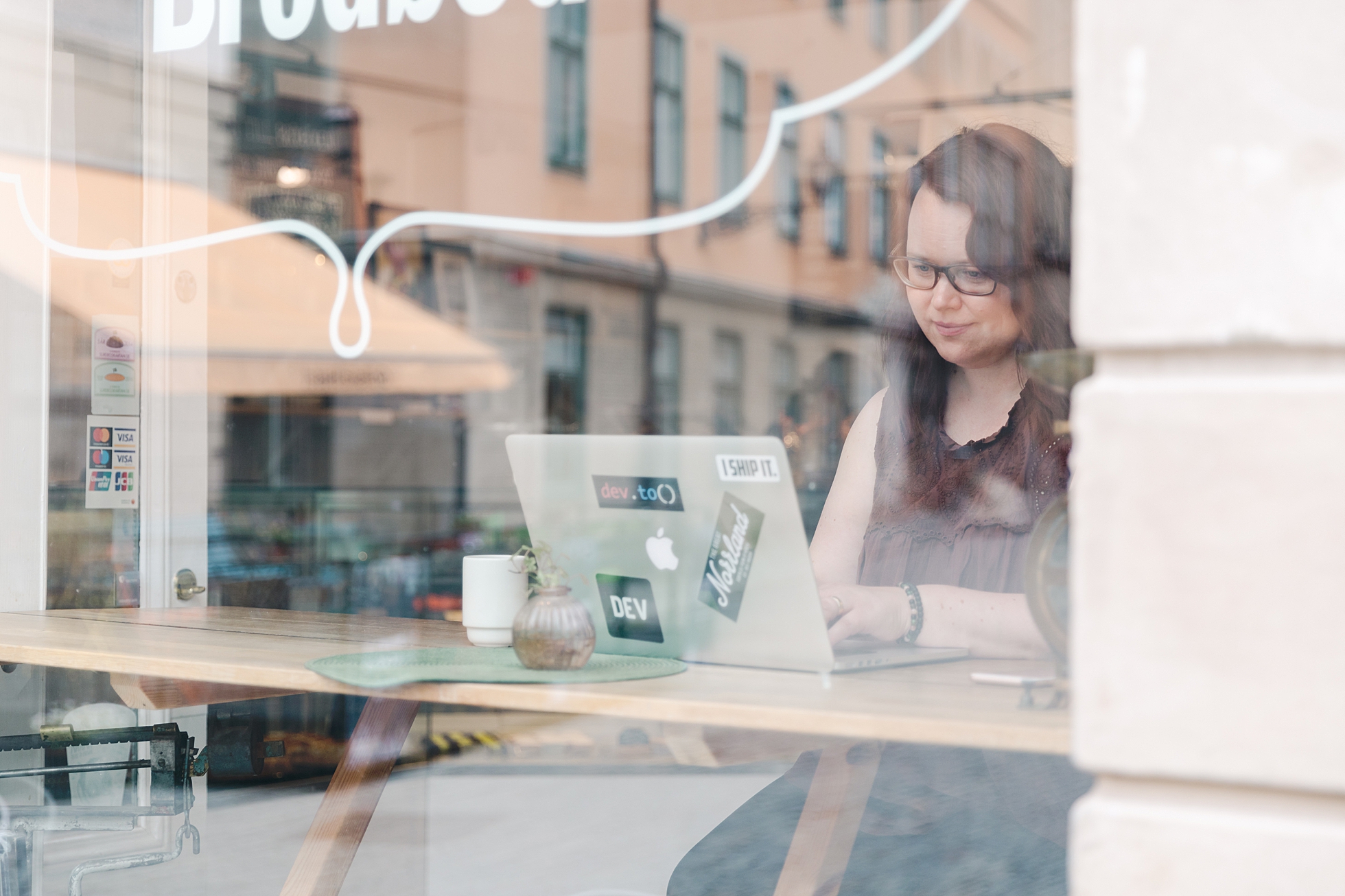 A brand photo of a woman sitting and working on her laptop at a cafe