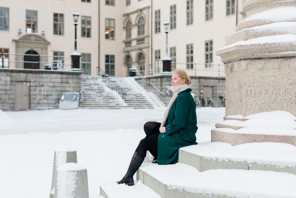 "a photo of a female entrepreneur sitting on the snowy steps at Riddarholmen"