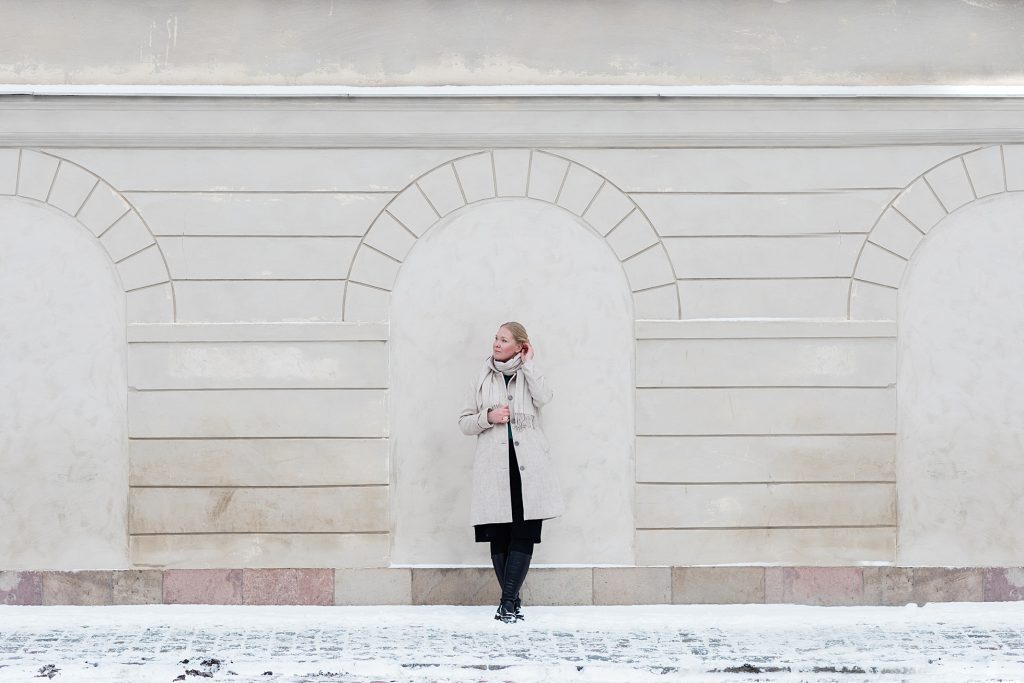 "a photo of a woman dressed in a beige coat and scarf in snowy Stockholm"