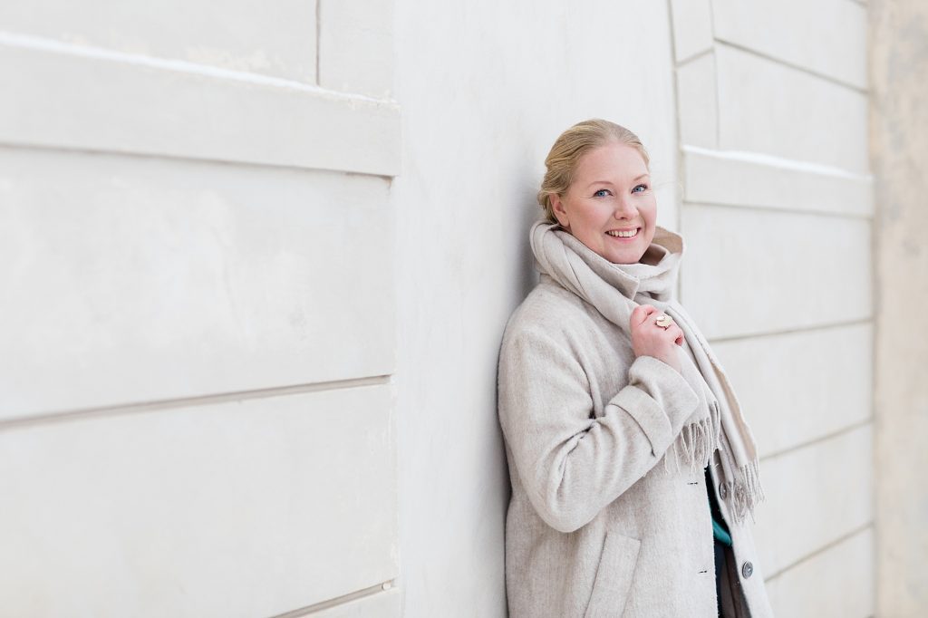 "a photo of a happy business owner dressed in a beige coat and scarf in Stockholm taken by Janine Laag at Lumeah Photography"