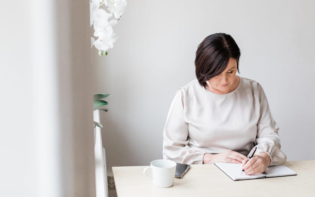 a professional photo of Monica from Pensionsguiden sitting at a desk and writing