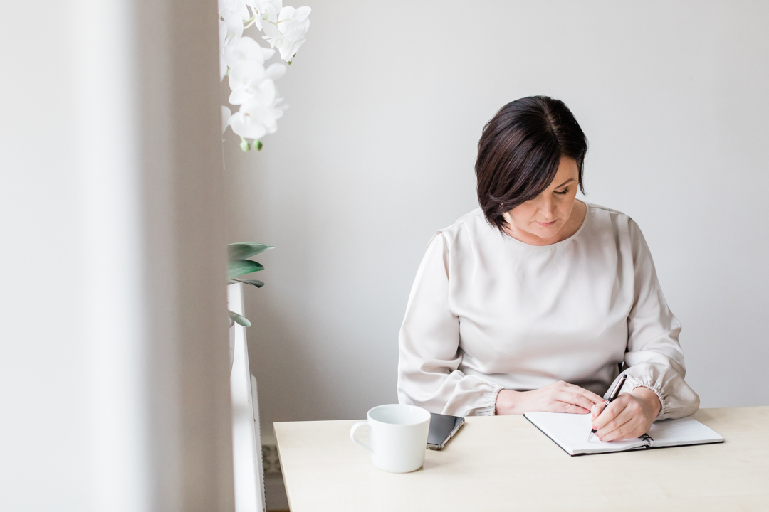 a professional photo of Monica from Pensionsguiden sitting at a desk and writing