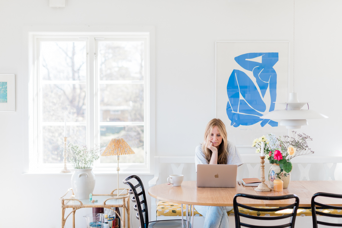 a bright but minimalistic professional photo of life coach Sara Flume working on her laptop in her home office