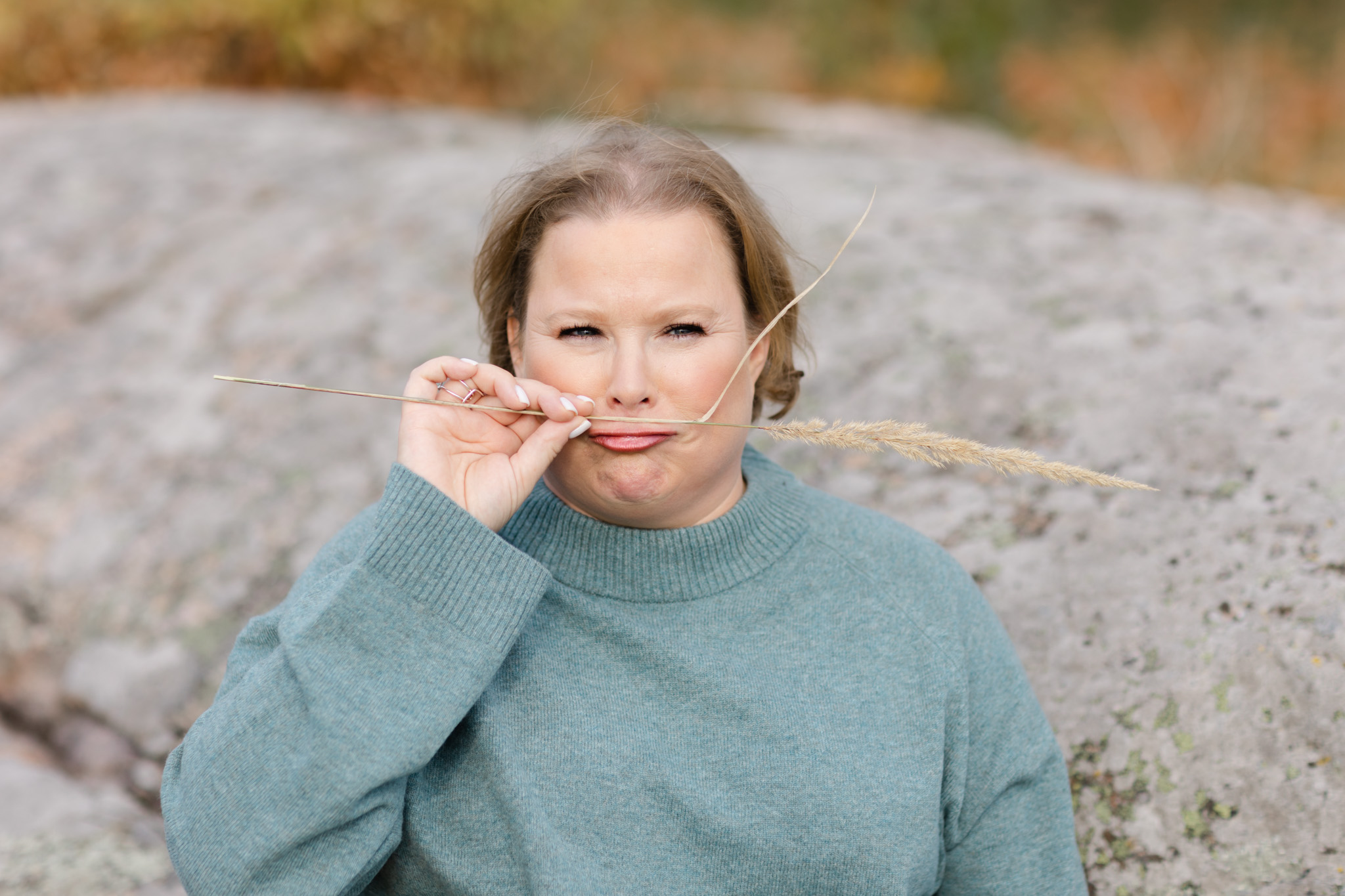professional but playful photo of economy coach Anna Arnetz holding a reed like a moustache