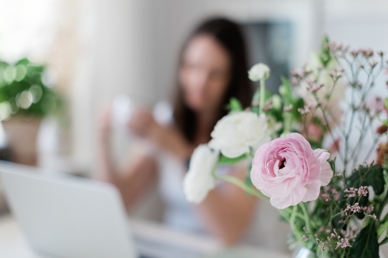 photo of flowers with photographer Janine Laag working on her laptop in the background