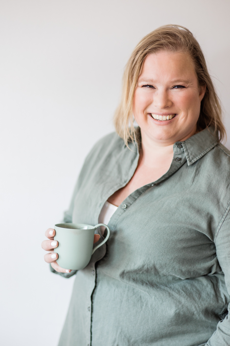 an unposed and spontaneous personal brand photo of coach Anna Arnetz holding a cup of coffee and smiling at the camera