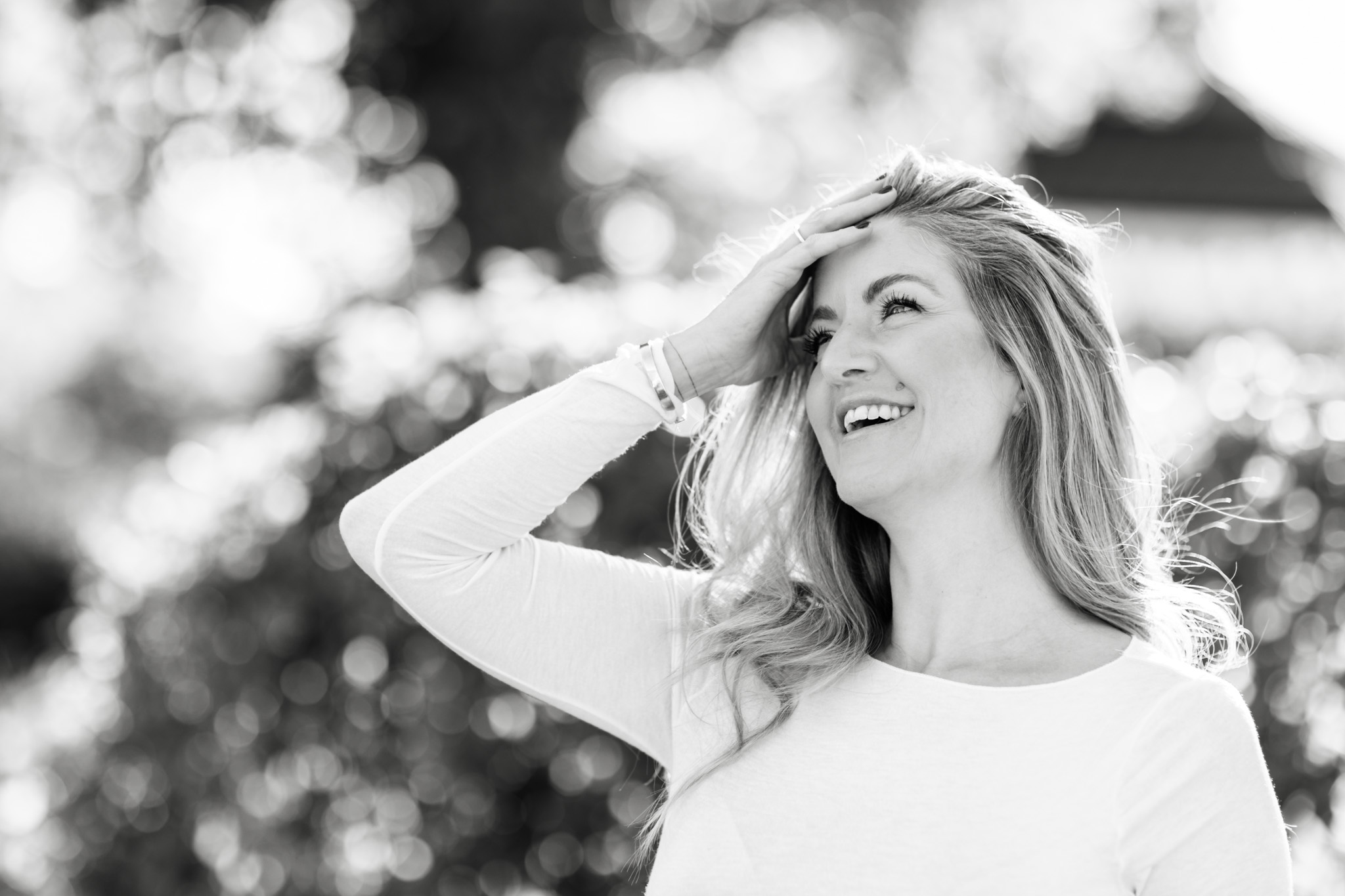 a black and white brand photo of medium Anna Stomsi as she's holding her hand to her head and laughing