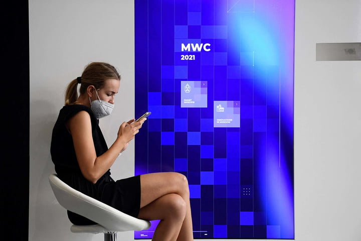 A woman wearing a mask uses her phone at the Mobile World Congress (MWC) fair in Barcelona on July 01, 2021.