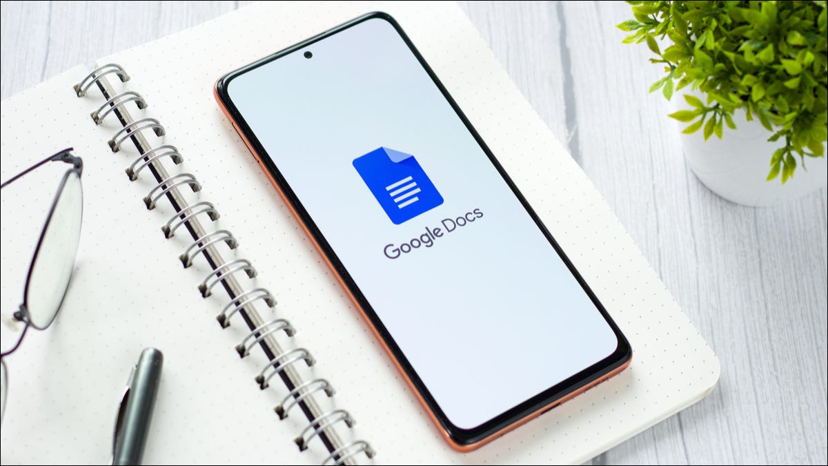 A smartphone lying on an open notebook and displaying the Google Docs logo.