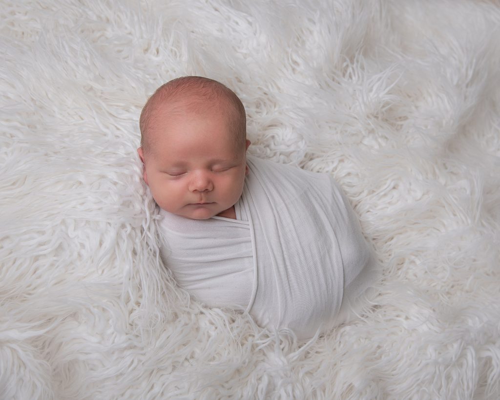 Sovande bebis på vit fäll