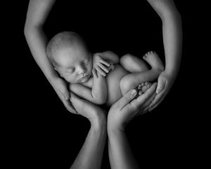 Nyfödd bebis vilande i pappas händer