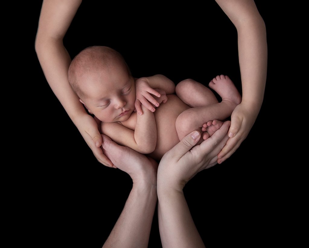 Nyfödd bebis i familjens händer