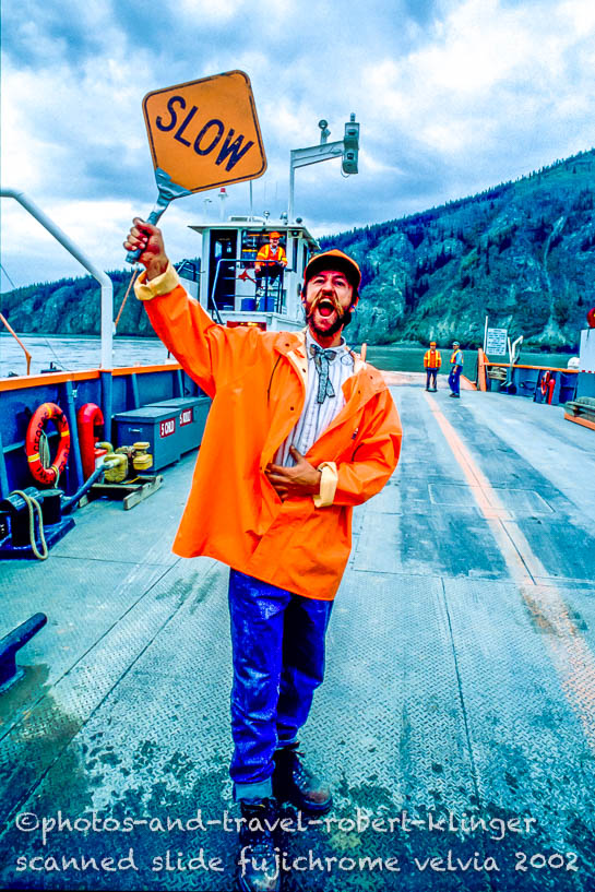 A worker shouting to slow the cars down, which enter the ferry over the Yukon river