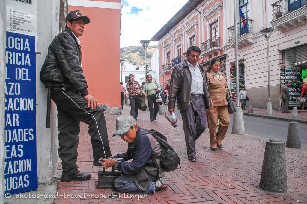 A boy cleaning the shoes of a police official in Quito, Equador