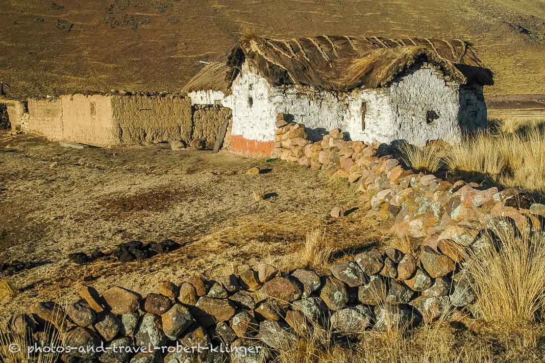 A stone wall and a rustic house in the Andes