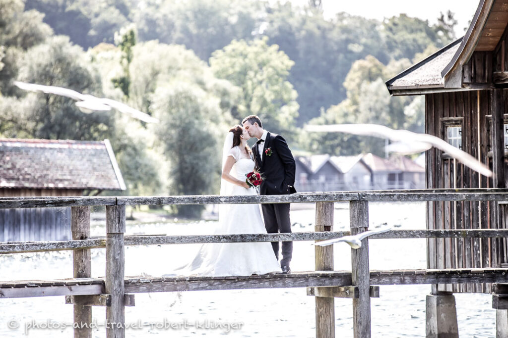 A bridal couple kissing on a jetty at lake Ammersee