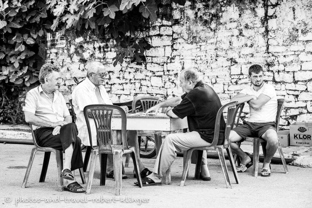 A group of men are playing cards on a road in Albania